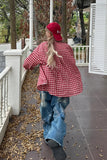 Person wearing a red checkered shirt and blue jeans walking on a porch.