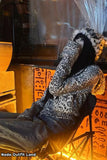 Person wearing a leopard print outfit sitting in a chair with warm lighting.