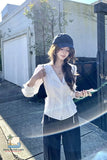 Woman in white blouse and blue cap standing outside a building