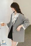 Woman wearing a gray blazer with lace details, holding a coffee cup.