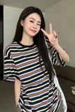 Woman wearing a striped shirt making a peace sign indoors.