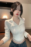 Woman wearing a white blouse with lace details and blue jeans indoors.