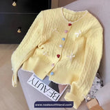 Yellow cardigan with colorful buttons on a surface