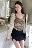Woman in floral top and black skirt standing indoors with a neutral background