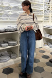 Woman in a striped shirt and jeans standing in a store with shelves of plates.