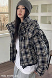Person wearing a plaid jacket and gray beanie indoors