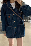 Person wearing a denim jacket with a brown shoulder bag indoors.
