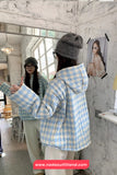 Person wearing a blue and white checkered jacket in a room with a mirror and poster on the wall.