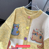 Children's cardigan with cat designs and buttons on a hanger