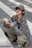 Person wearing a plaid shirt and cap on a street with 'Nado Outfit Land' branding.