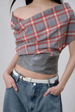 Person wearing a plaid top and denim pants against a plain background