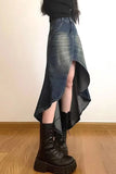 Person wearing a denim skirt with a high-low hem and black boots on a wooden floor.