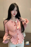Woman wearing a pink cardigan with decorative buttons indoors