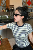 Person wearing sunglasses and a striped shirt in a cafe setting