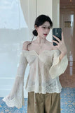 Woman taking a mirror selfie wearing a light-colored off-shoulder top and brown pants.