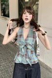 Woman in plaid top and jeans standing outdoors with a handbag.