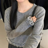 Person wearing a gray sweater with decorative cuffs and hem.