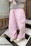 Person wearing pink checkered pants with small patterns, standing on a wooden platform.