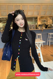 Woman wearing a black cardigan with colorful buttons in a casual setting.