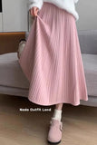 Person wearing a pink pleated skirt and matching shoes on a neutral background