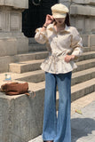 Person wearing a white blouse and blue jeans standing on stone steps.