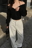 Person wearing a black off-shoulder top and light-colored pants on a street.