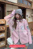 Woman wearing a pink sweater with cartoon designs in an outdoor setting.