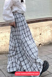 Person wearing a white blouse and plaid skirt on a sidewalk.