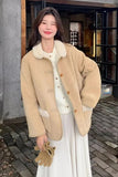 Woman wearing a beige coat with a white interior, standing on a street.