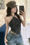 Woman taking a mirror selfie wearing a denim halter top and cap.