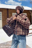 Person wearing a plaid jacket and beanie in a snowy outdoor setting.