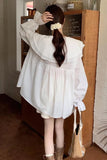 Person wearing a white outfit with ruffled details in an indoor setting.