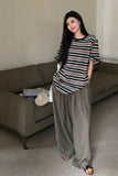 Woman in a striped shirt and wide-leg pants standing in a living room.
