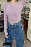 Person wearing a striped long-sleeve top and blue jeans in a room with furniture.
