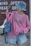 Person wearing a pink striped shirt and denim shorts, standing in front of a brick wall.