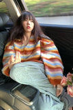 Person sitting in a car wearing a colorful striped sweater with a blurred outdoor background