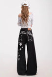 Person wearing black pants with star designs and a white top on a white background