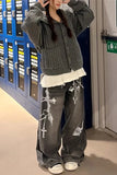 Person wearing a dark gray cardigan, white shirt, and dark gray pants with white patterns in a room with blue lockers.