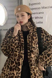 Person wearing a leopard print coat and beige cap in front of a coffee shop sign.