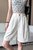 Person wearing a star-patterned crop top and white shorts, standing indoors.