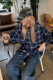Person wearing a plaid shirt and jeans sitting on a chair indoors.