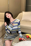 Woman in a colorful striped dress sitting on a couch with fruits on a table.