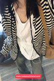 Person wearing a black and white striped blazer over a white shirt, with a beige bag.