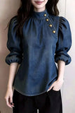 Person wearing a blue denim blouse with gold buttons against a plain background