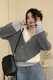 Woman wearing a gray and white sweater with a black bag indoors.