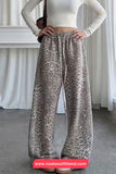 Person wearing leopard print pants and a white top in a minimalistic setting.