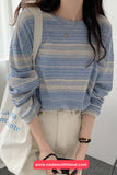 Person wearing a blue striped sweater holding a white bag with text.