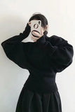 Person wearing a black sweater and skirt against a white background