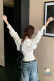Woman in a white shirt and blue jeans adjusting a framed picture on a wall.