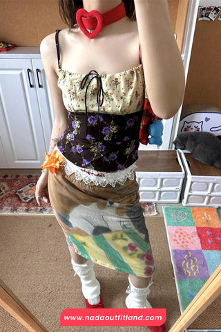 Person wearing a floral corset and colorful skirt in a room with a cat and toys.
